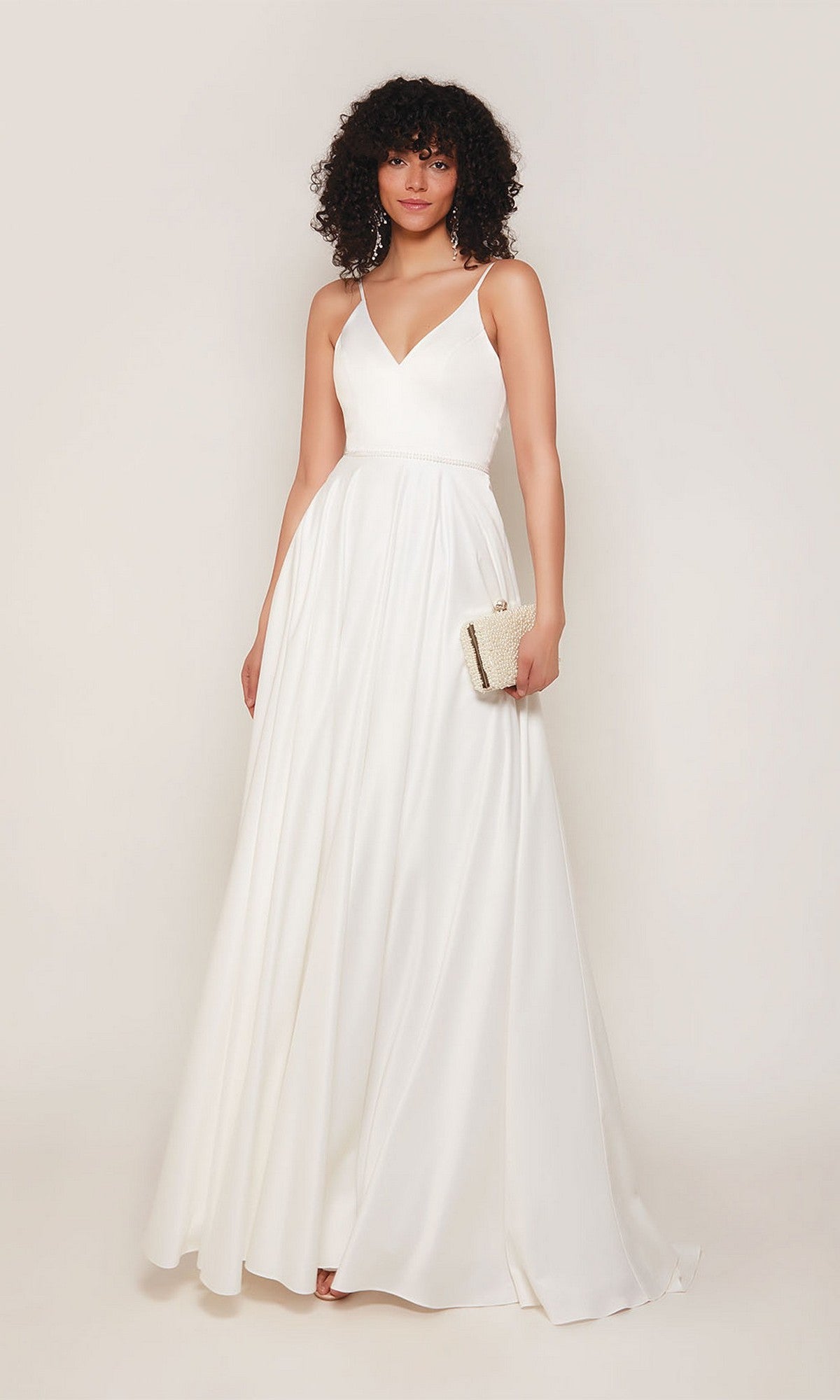 A woman in the Alyce 7089 long formal dress, a sleeveless white satin gown with a V-neckline, holds a small clutch purse while standing against a plain background.